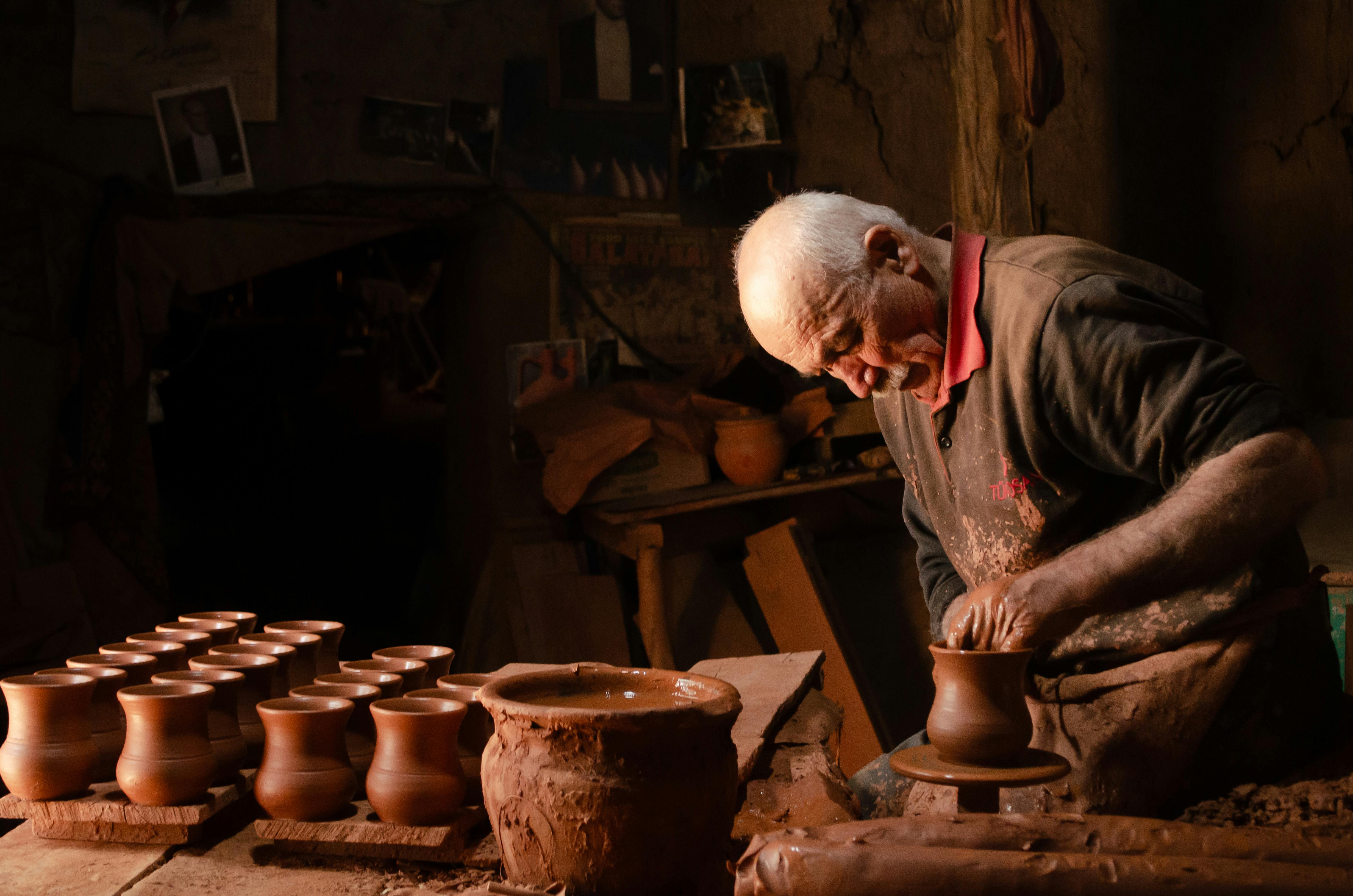 Alfarero veterano moldeando piezas de barro en su taller, con las manos cubiertas de arcilla