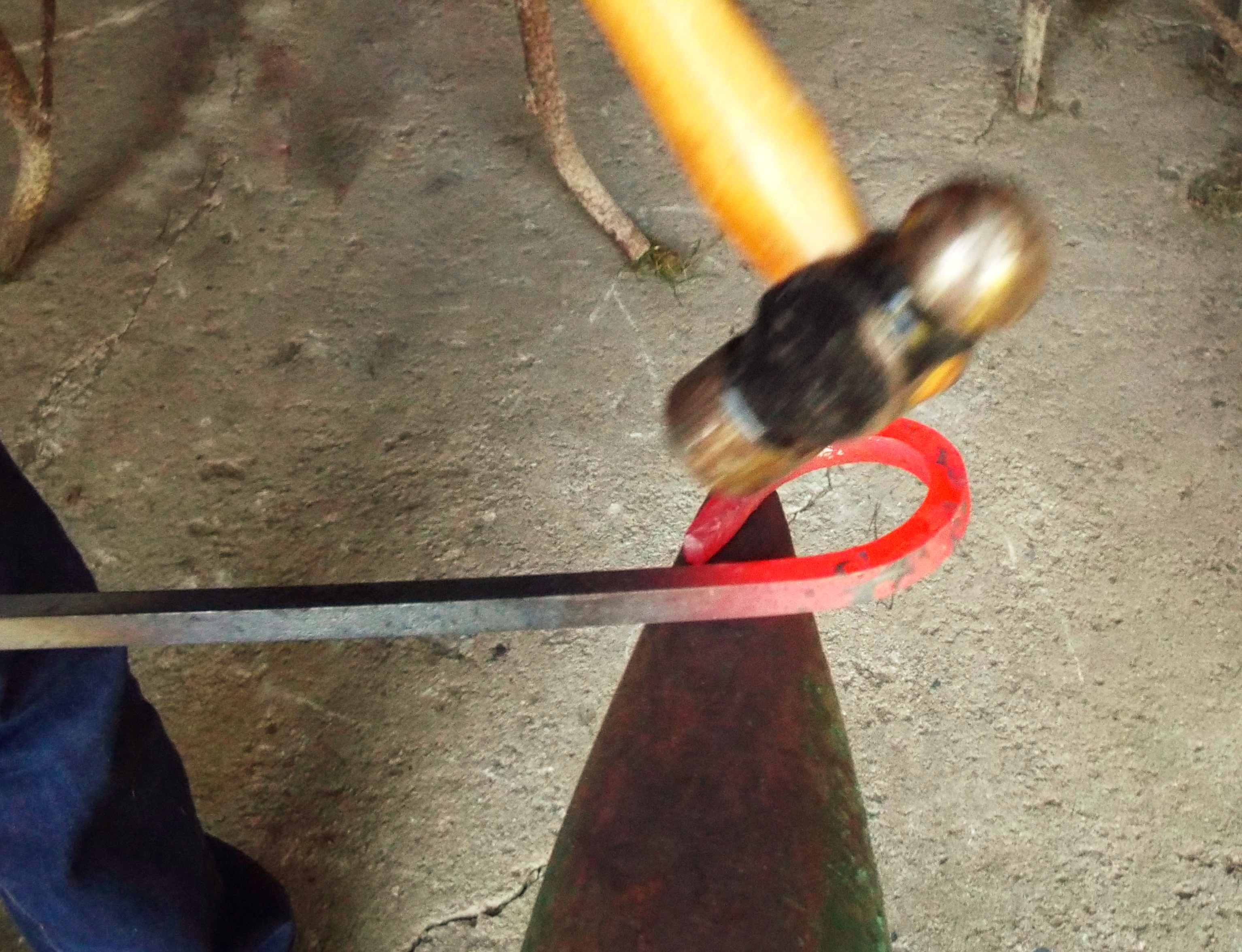 Herrero forjando hierro al rojo vivo sobre el yunque