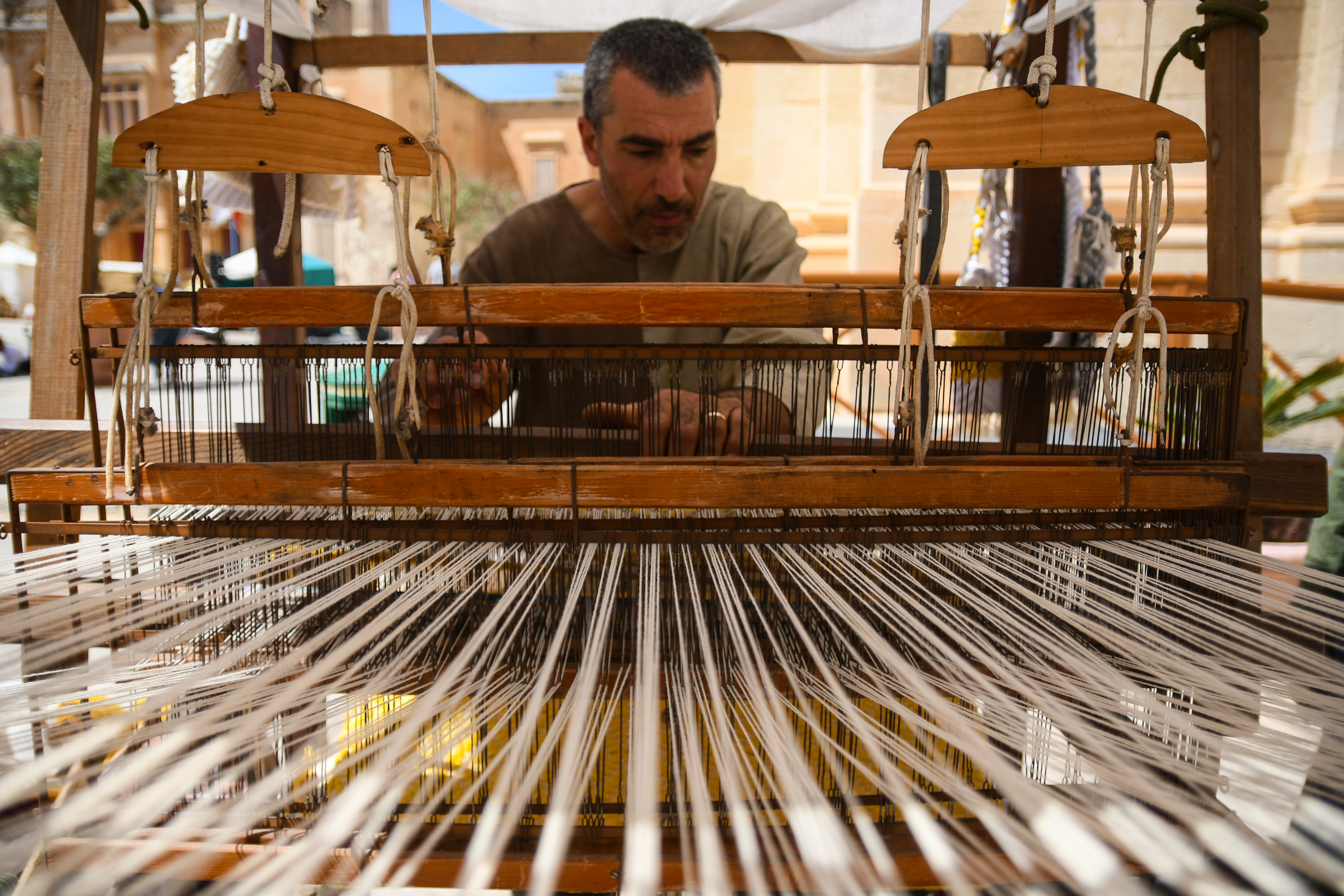 Manos de artesano tejiendo lana en telar tradicional